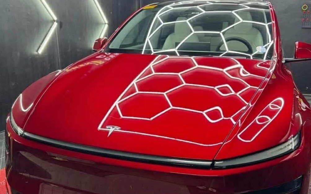 Red Tesla with a fresh graphene ceramic coating under the studio's hexagon lights