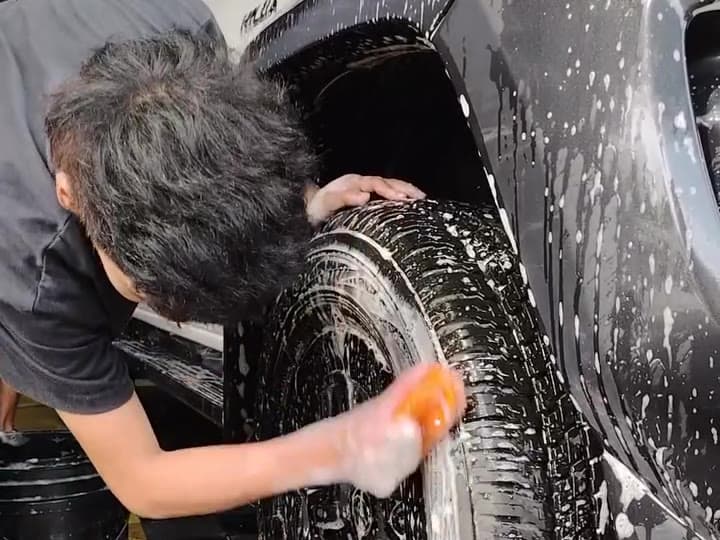 Detailer scrubbing a tire by hand